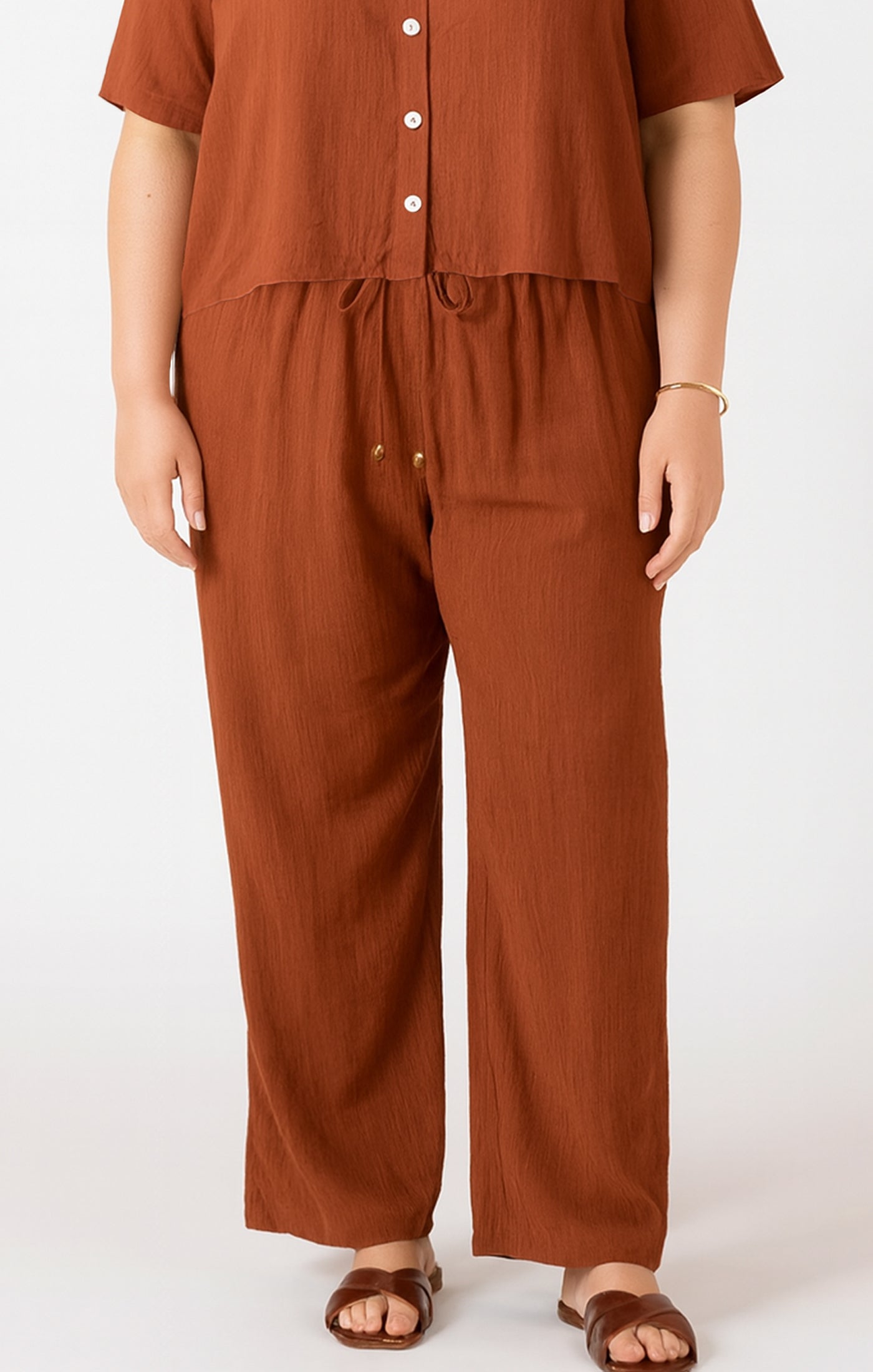 Person wearing a brown outfit with wide-leg pants on a white background