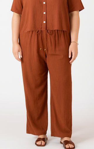 Person wearing a brown outfit with wide-leg pants on a white background