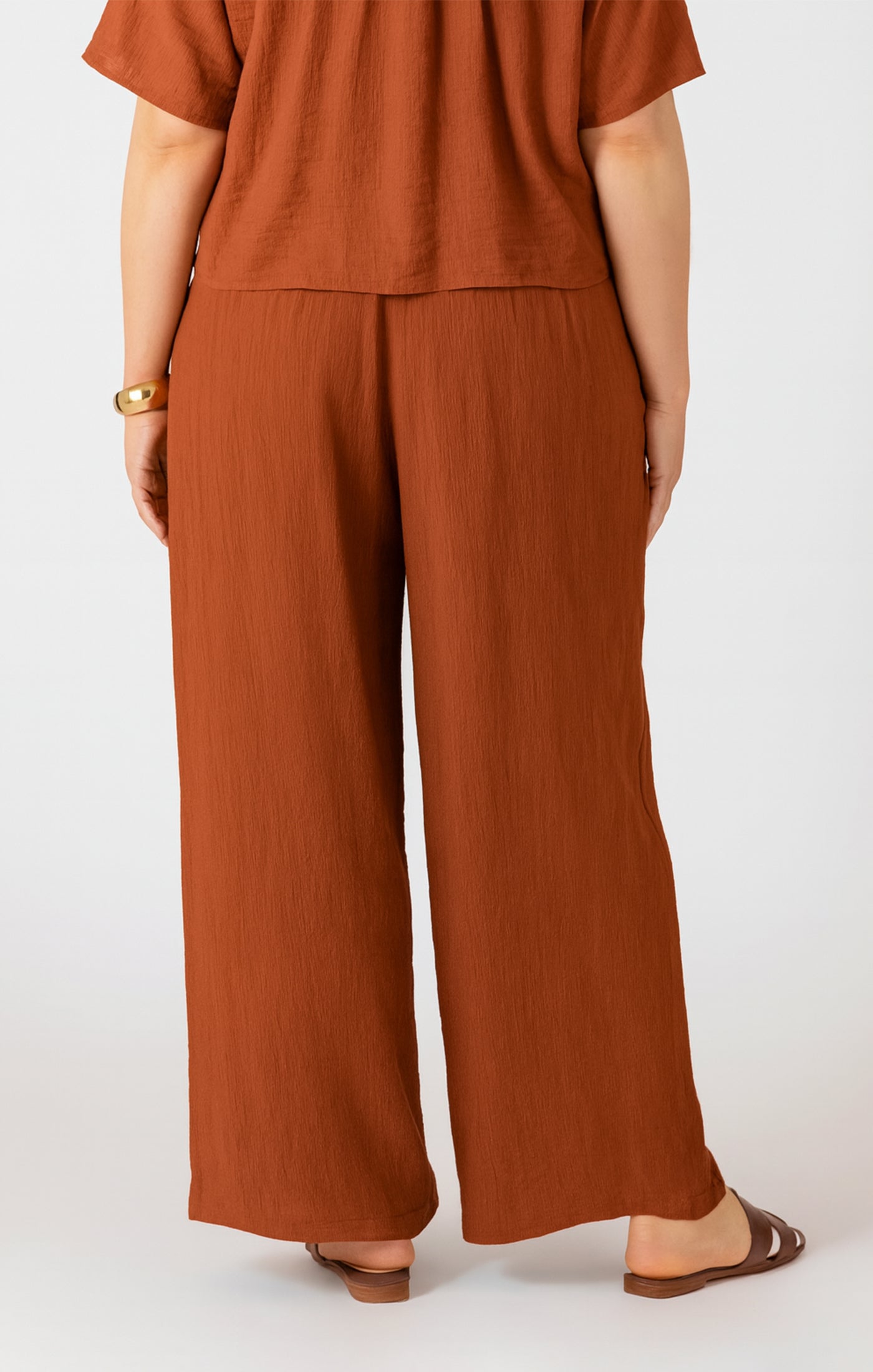 Person wearing a brown outfit with wide-leg pants on a white background