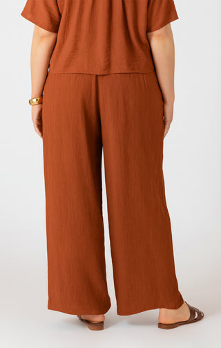 Person wearing a brown outfit with wide-leg pants on a white background