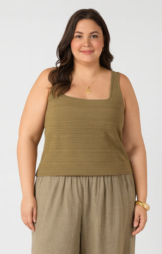 Woman wearing a green sleeveless top and beige pants on a white background