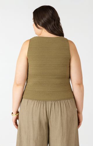 Woman wearing a green sleeveless top and beige pants on a white background