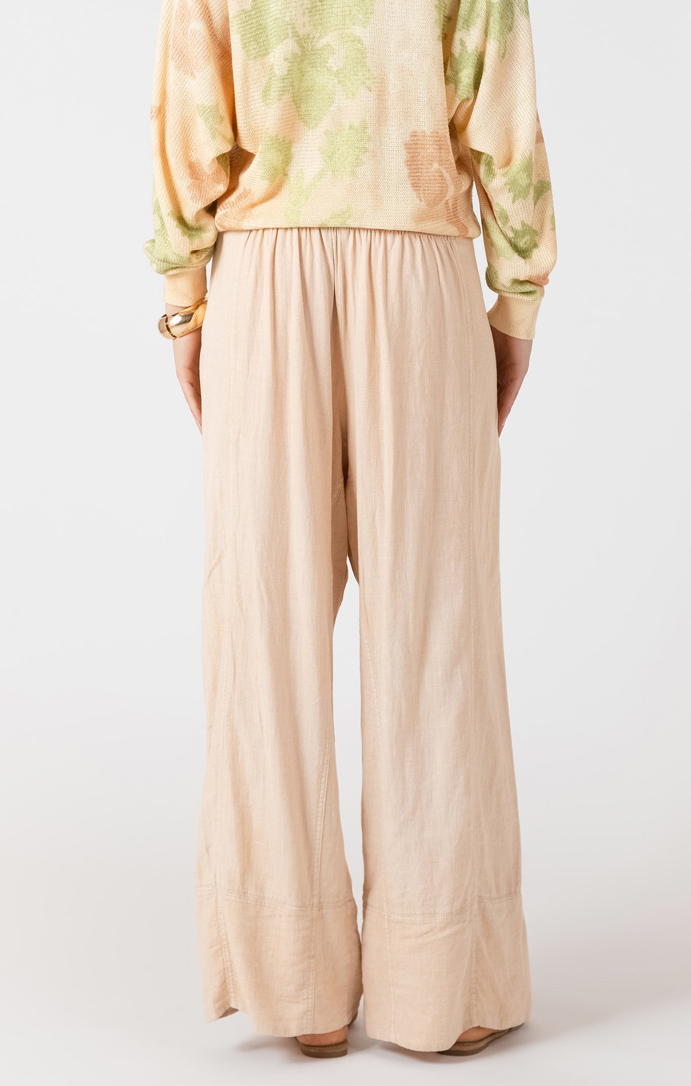 Beige wide-leg pants worn with a light-colored top on a white background