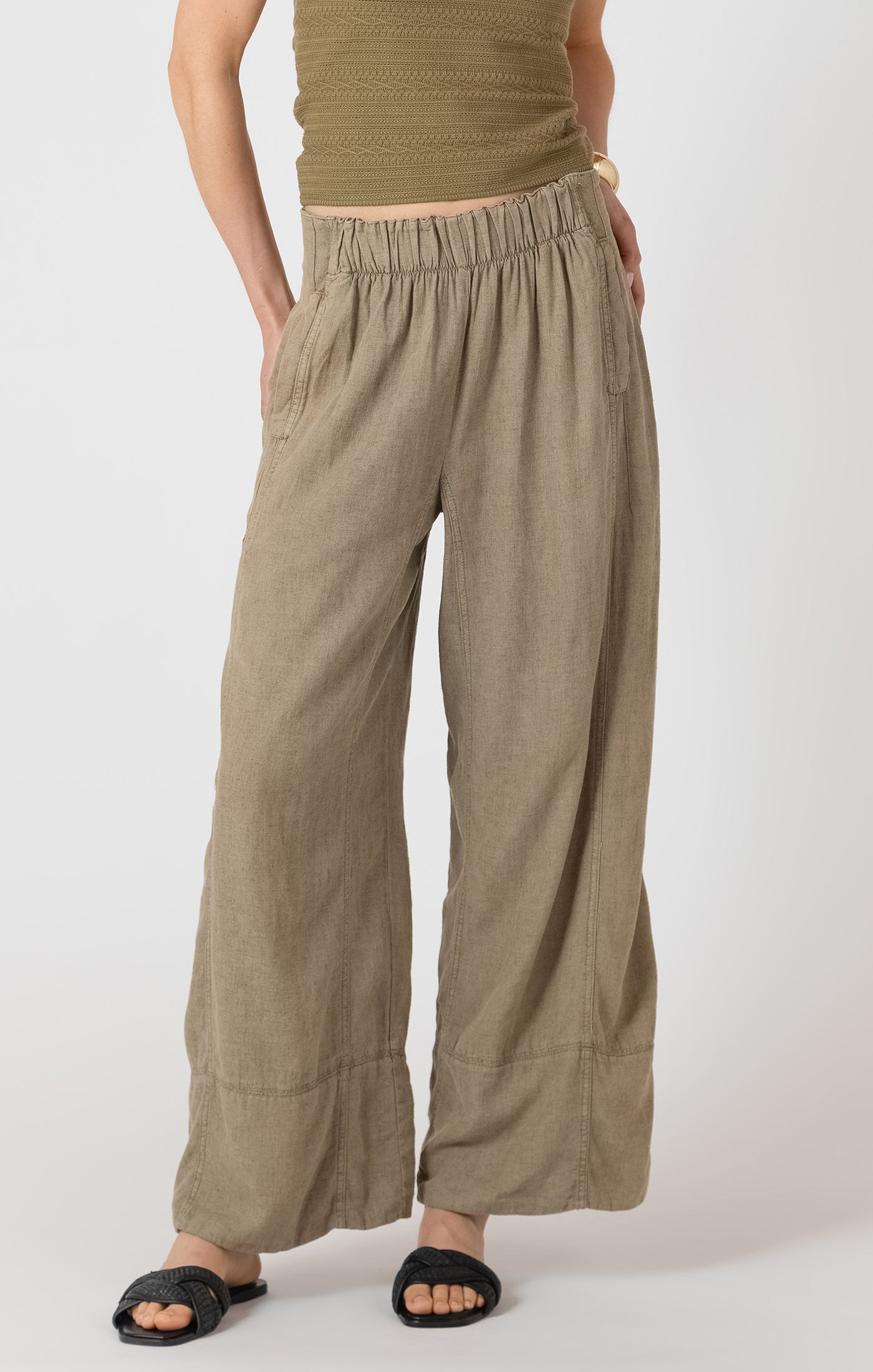 Person wearing olive green pants and a matching top on a white background
