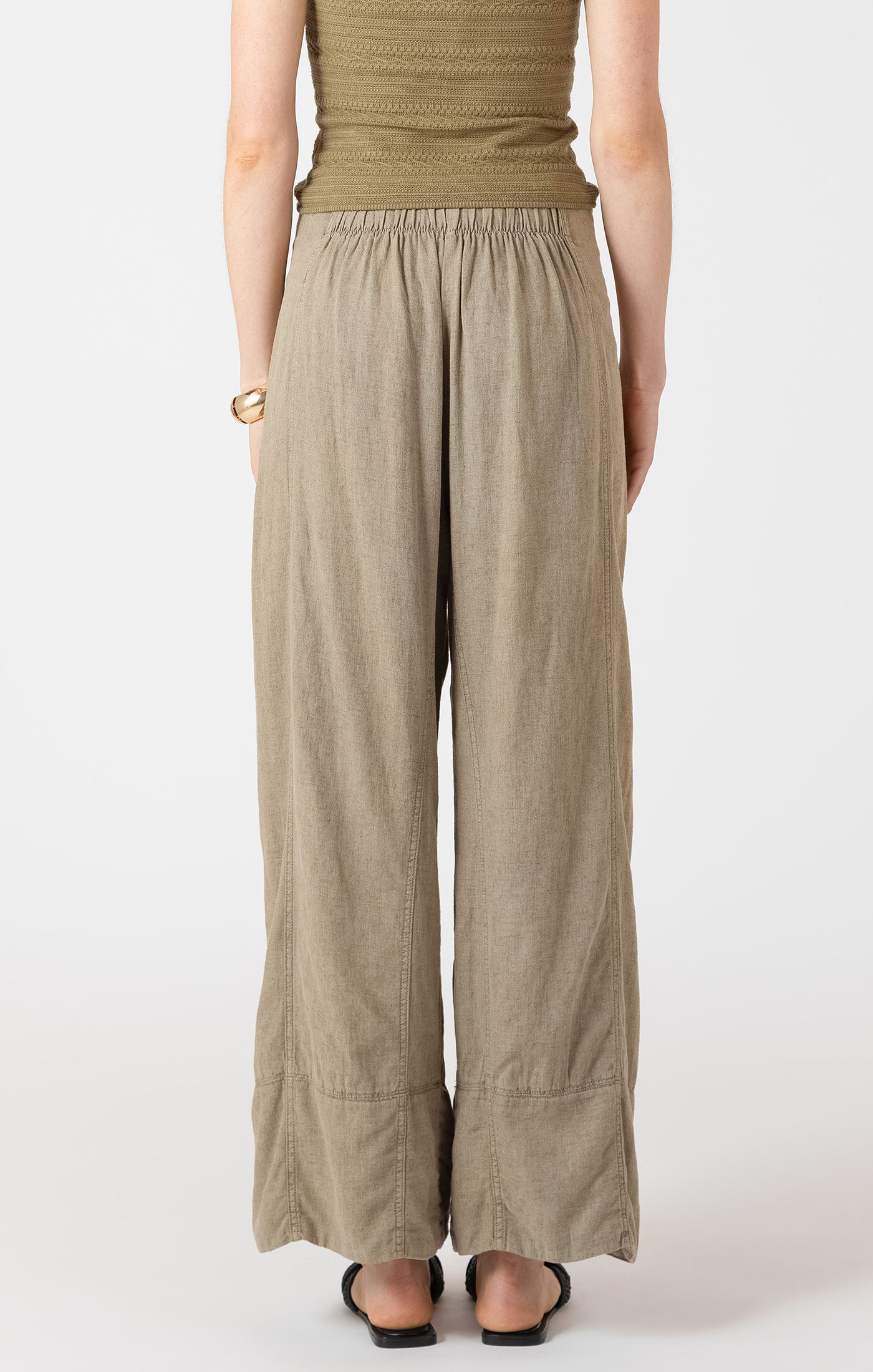 Person wearing a green top and beige wide-leg pants on a white background