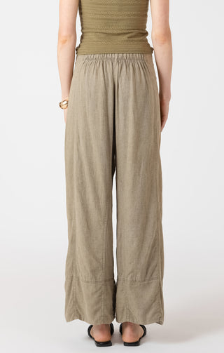 Person wearing a green top and beige wide-leg pants on a white background