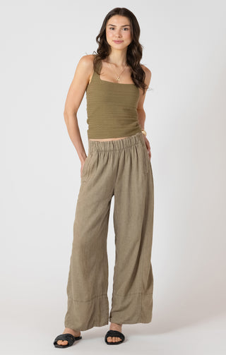 Woman wearing a green tank top and wide-leg pants on a white background