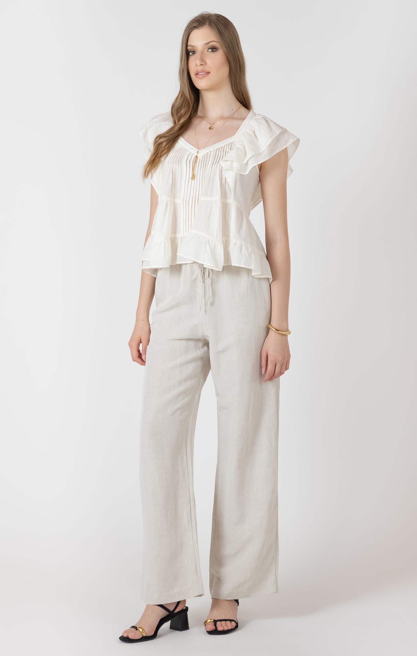Woman wearing a white blouse and beige pants on a white background