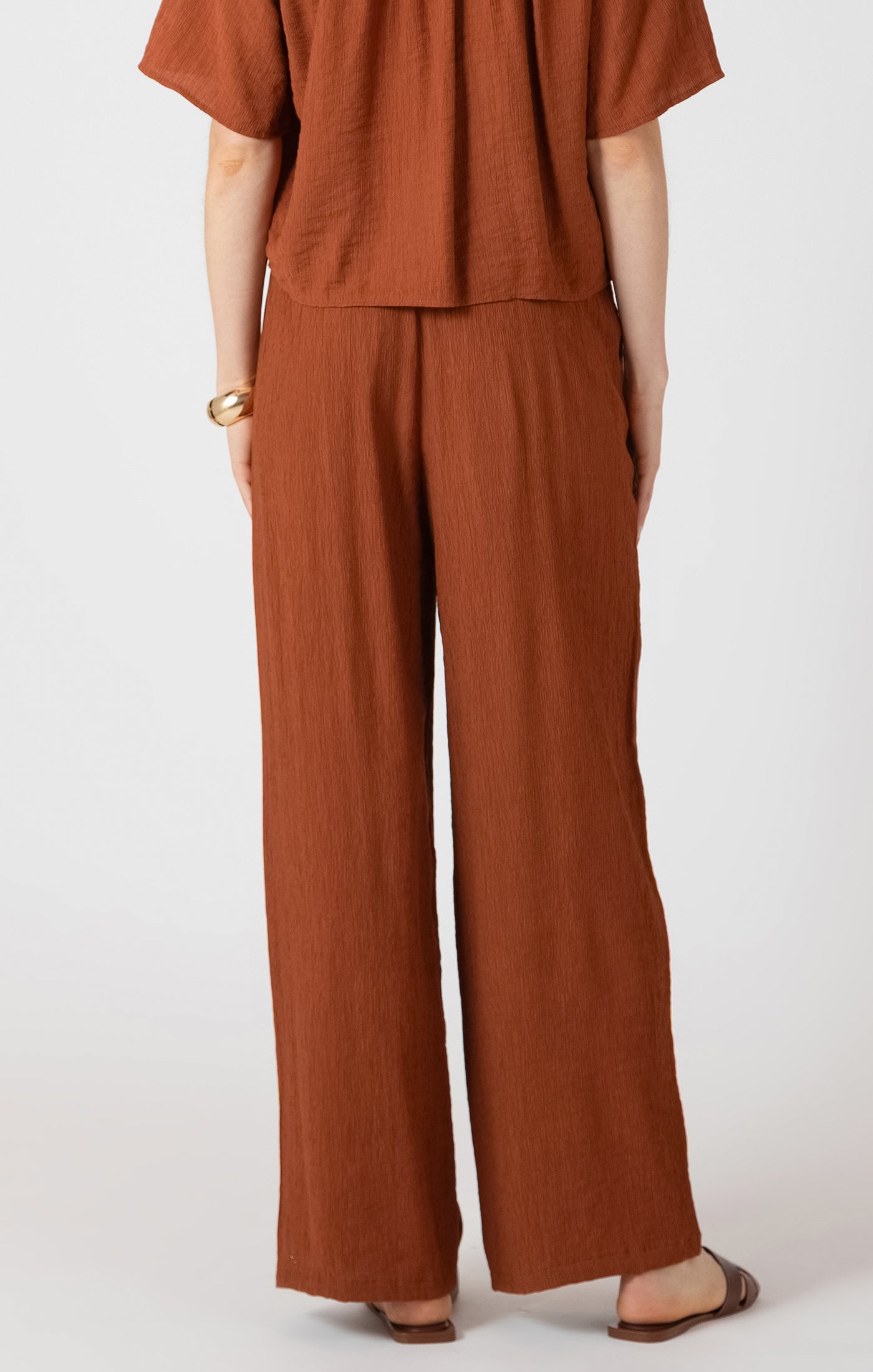 Person wearing a brown outfit with wide-leg pants on a white background