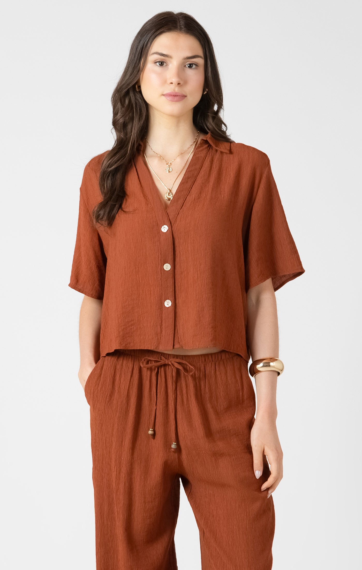 Woman wearing a brown outfit with a top and pants on a white background