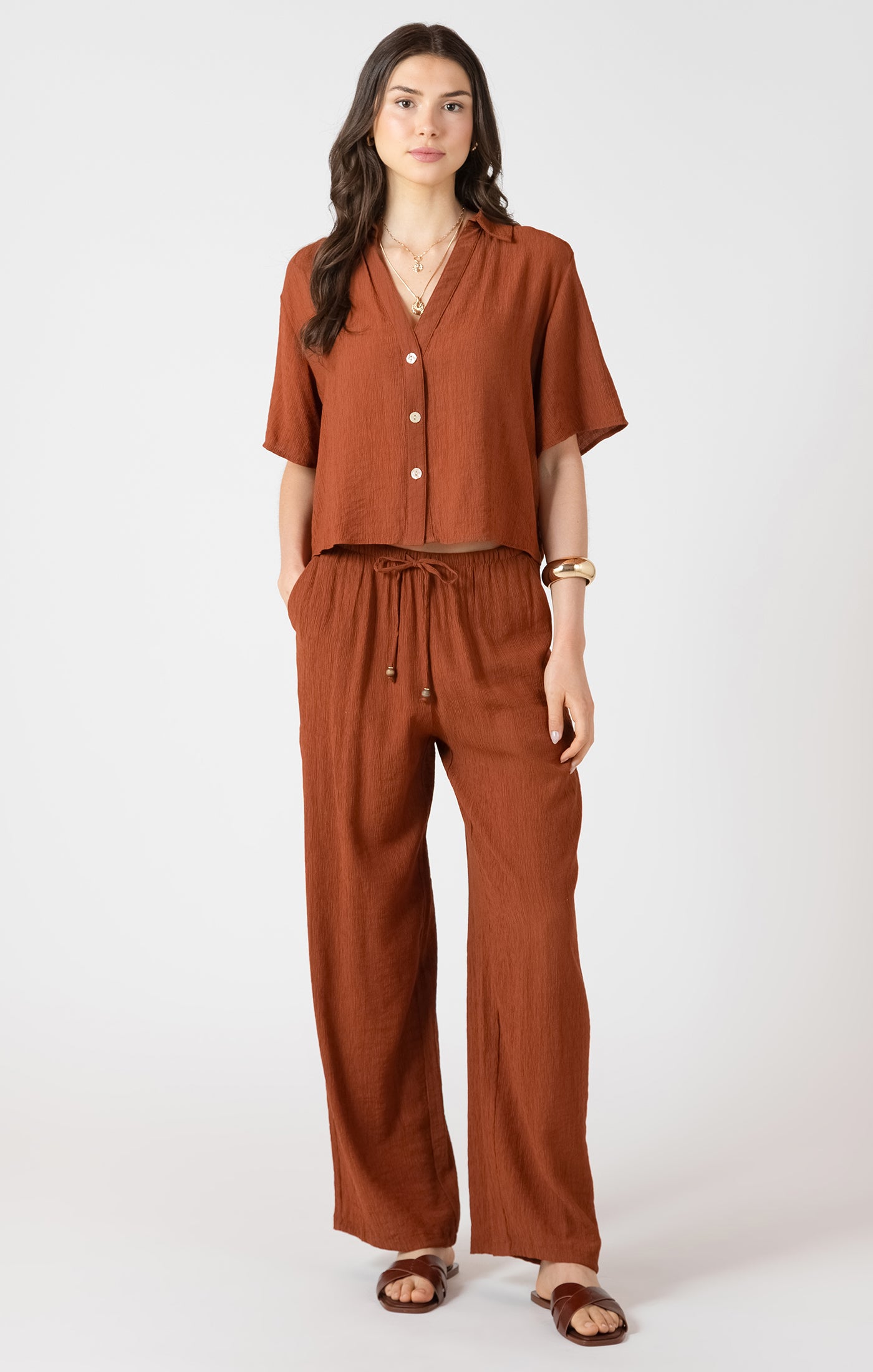 Woman wearing a brown outfit with a top and pants on a white background