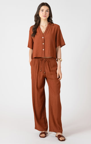 Woman wearing a brown outfit with a top and pants on a white background