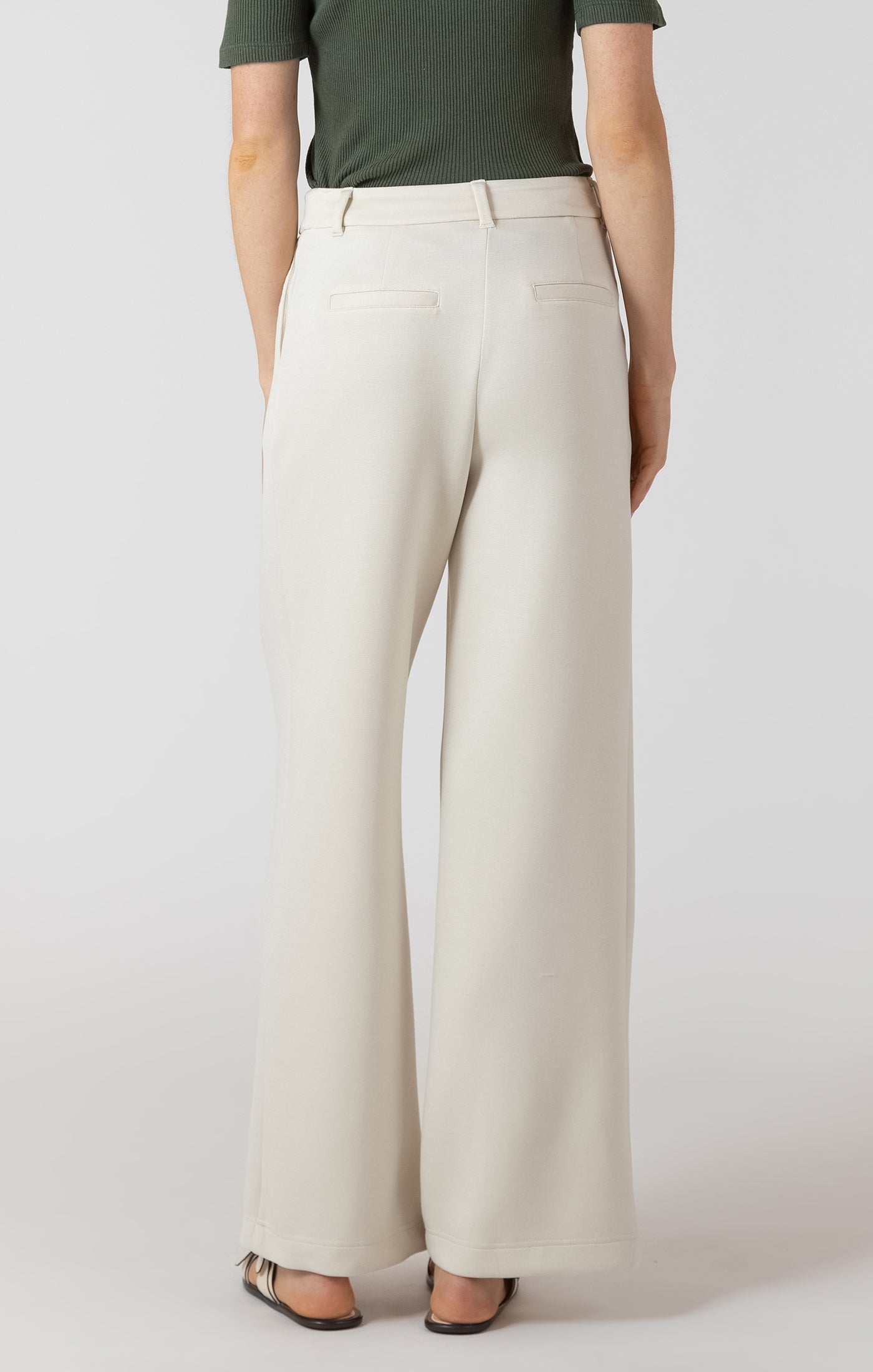Person wearing white pants and a green top on a plain background