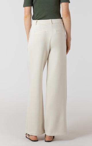 Person wearing white pants and a green top on a plain background