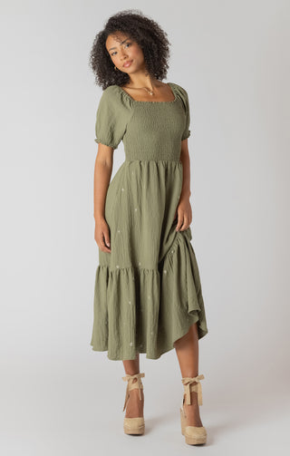 Woman wearing a green dress with puff sleeves on a white background
