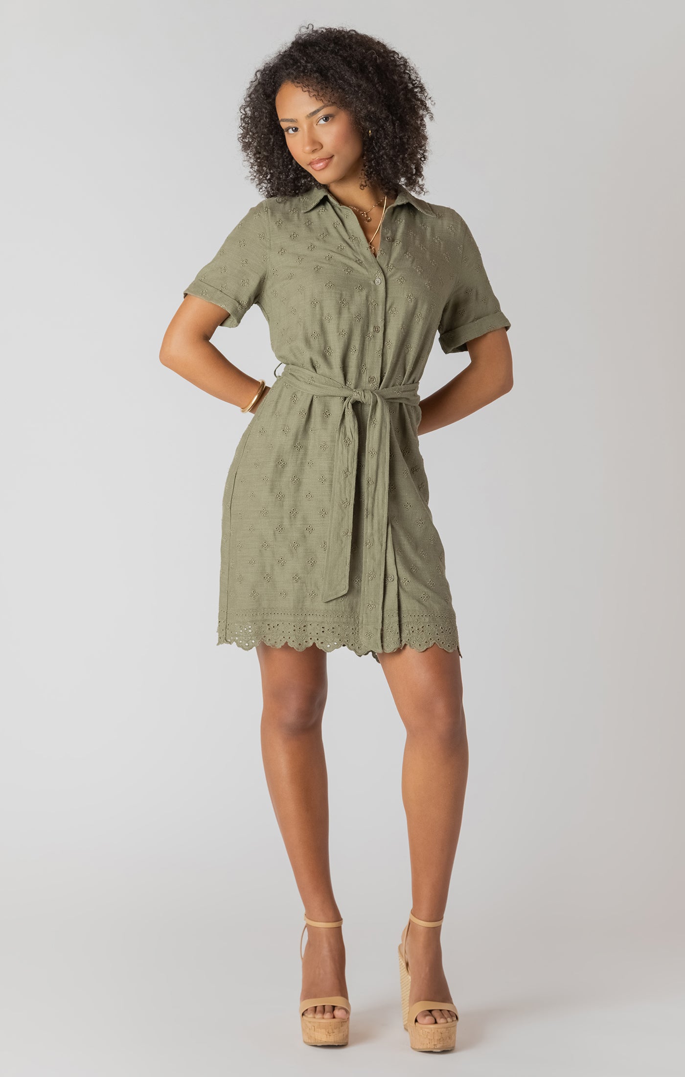 Woman wearing a green dress with a belt on a white background