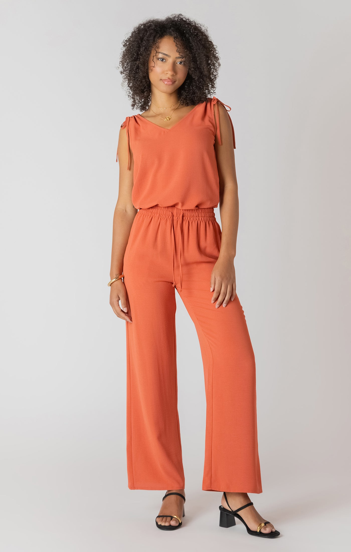 Woman wearing an orange jumpsuit on a plain background
