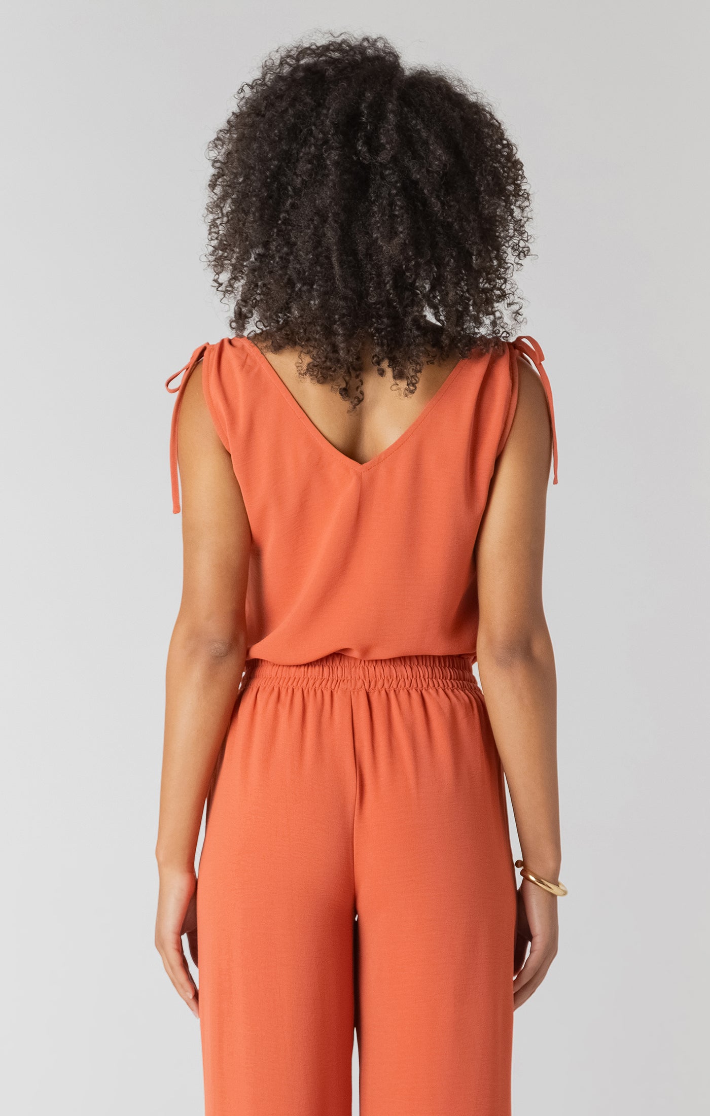 Person wearing an orange jumpsuit on a plain background