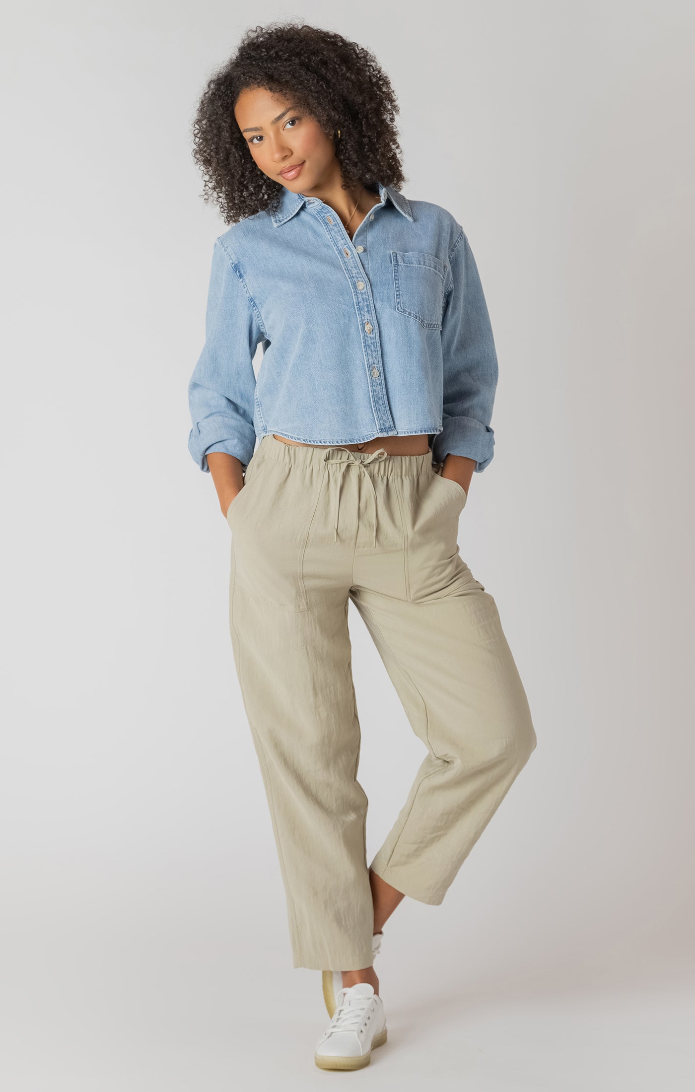 Woman wearing a light blue shirt and beige pants on a white background