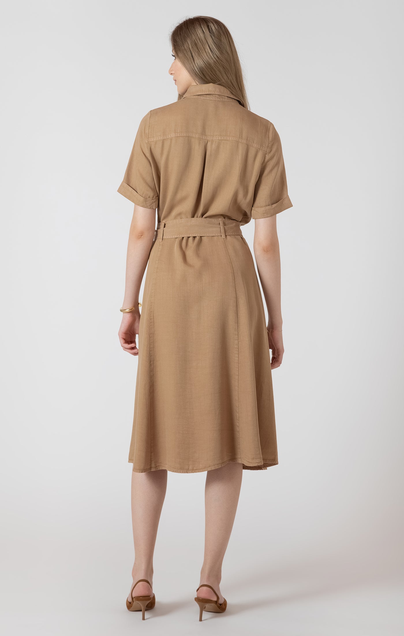Woman wearing a beige dress with a belt on a white background