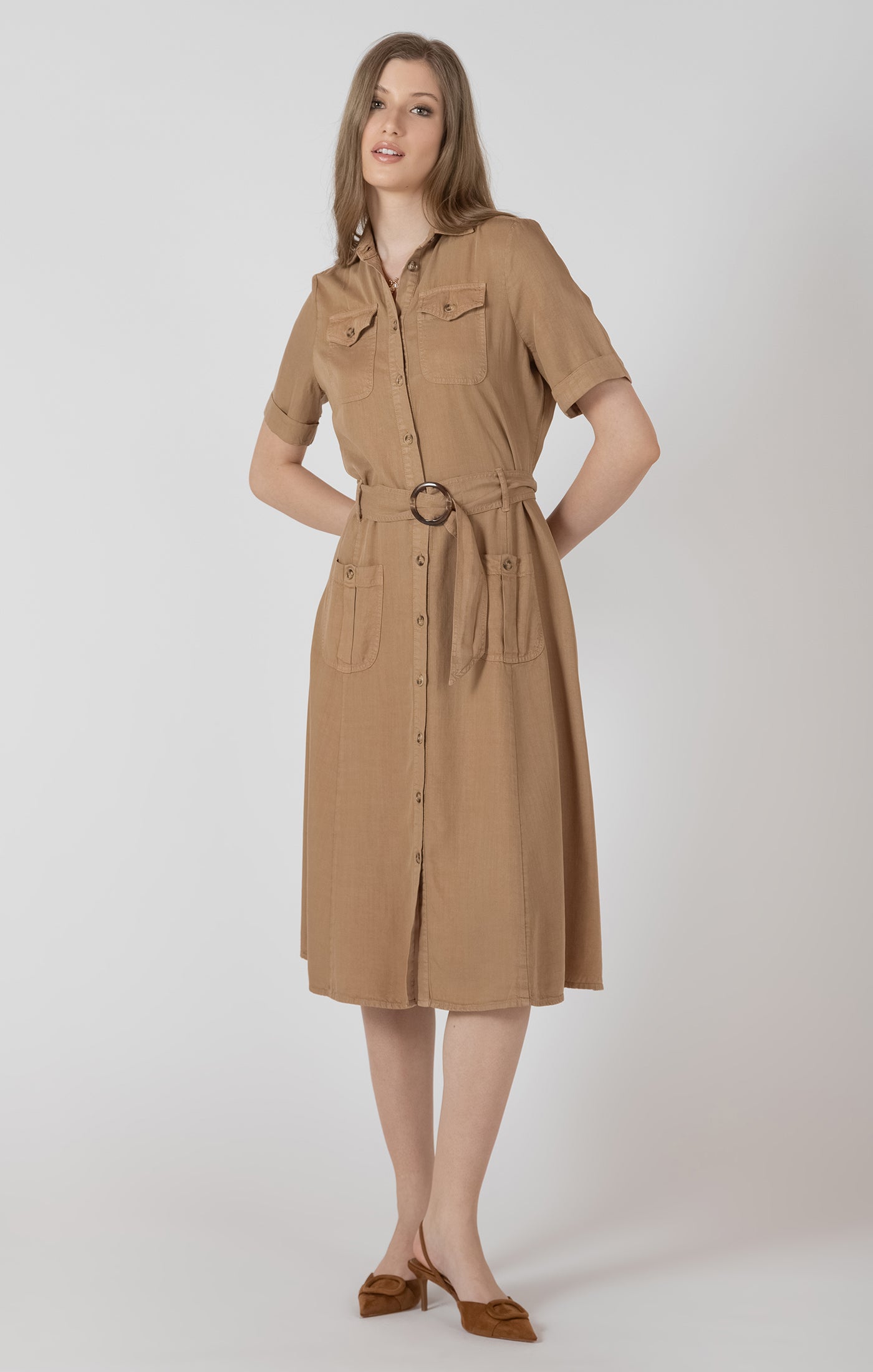 Woman wearing a beige dress with a belt on a white background