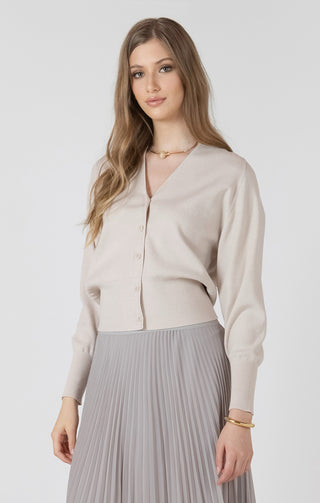 Woman wearing a beige cardigan and gray pleated skirt on a white background