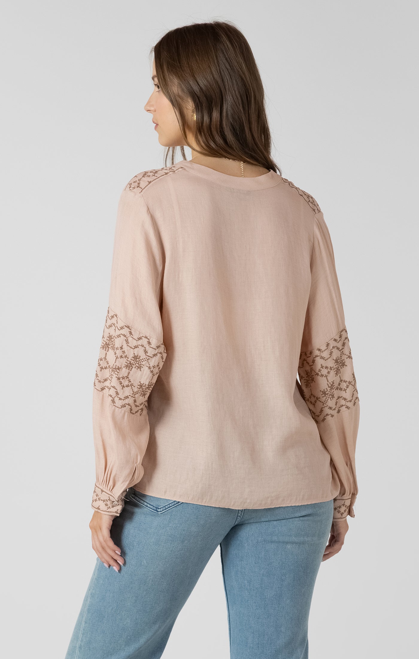 Woman wearing a beige blouse with lace sleeves on a white background