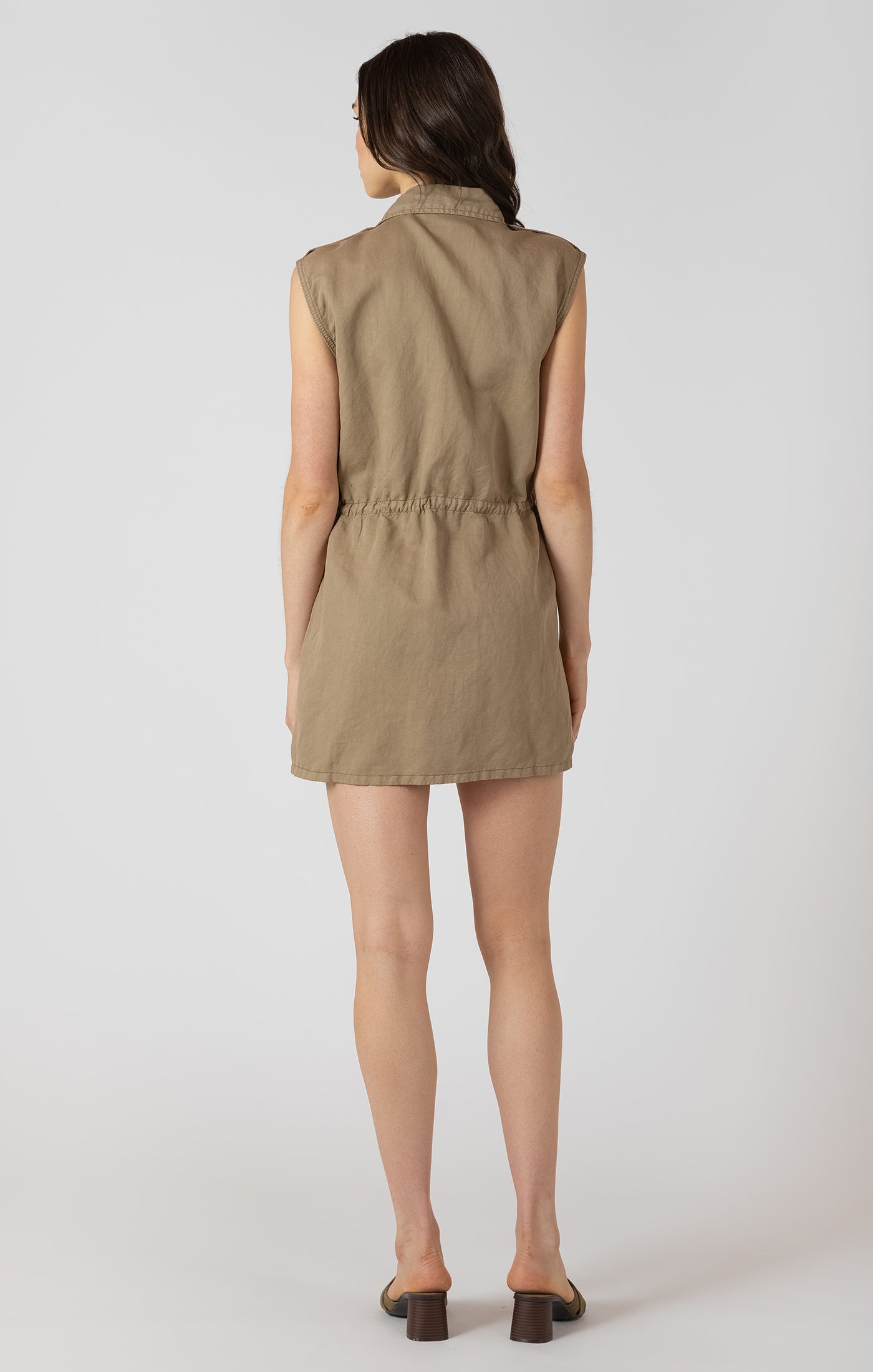 Woman wearing a beige sleeveless romper on a white background