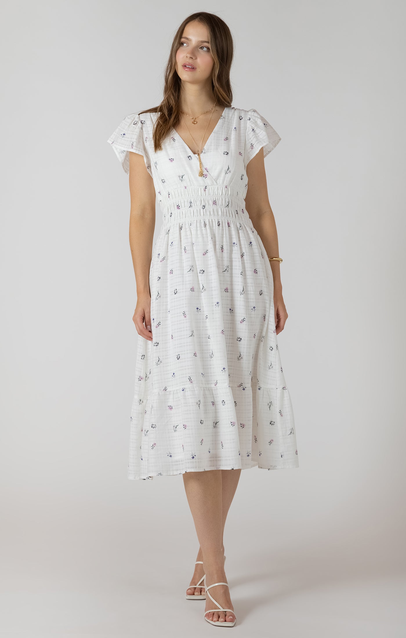 Woman wearing a white dress with a subtle pattern on a plain background