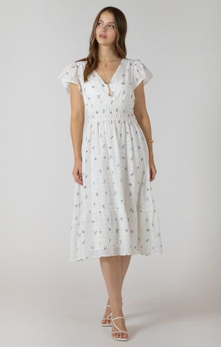 Woman wearing a white dress with a subtle pattern on a plain background