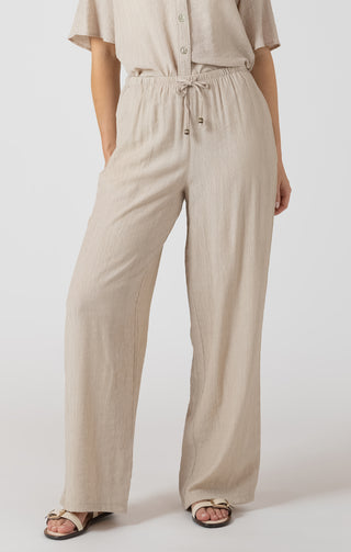 Person wearing a beige outfit with wide-leg pants on a white background