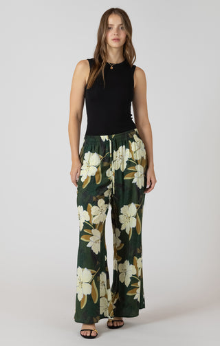 Woman wearing a black sleeveless top and floral wide-leg pants on a white background
