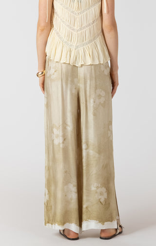 Woman wearing a beige top and wide-leg pants on a white background