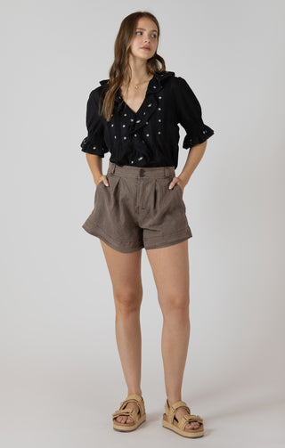 Women wearing a black blouse with white embroidered flowers on it. 