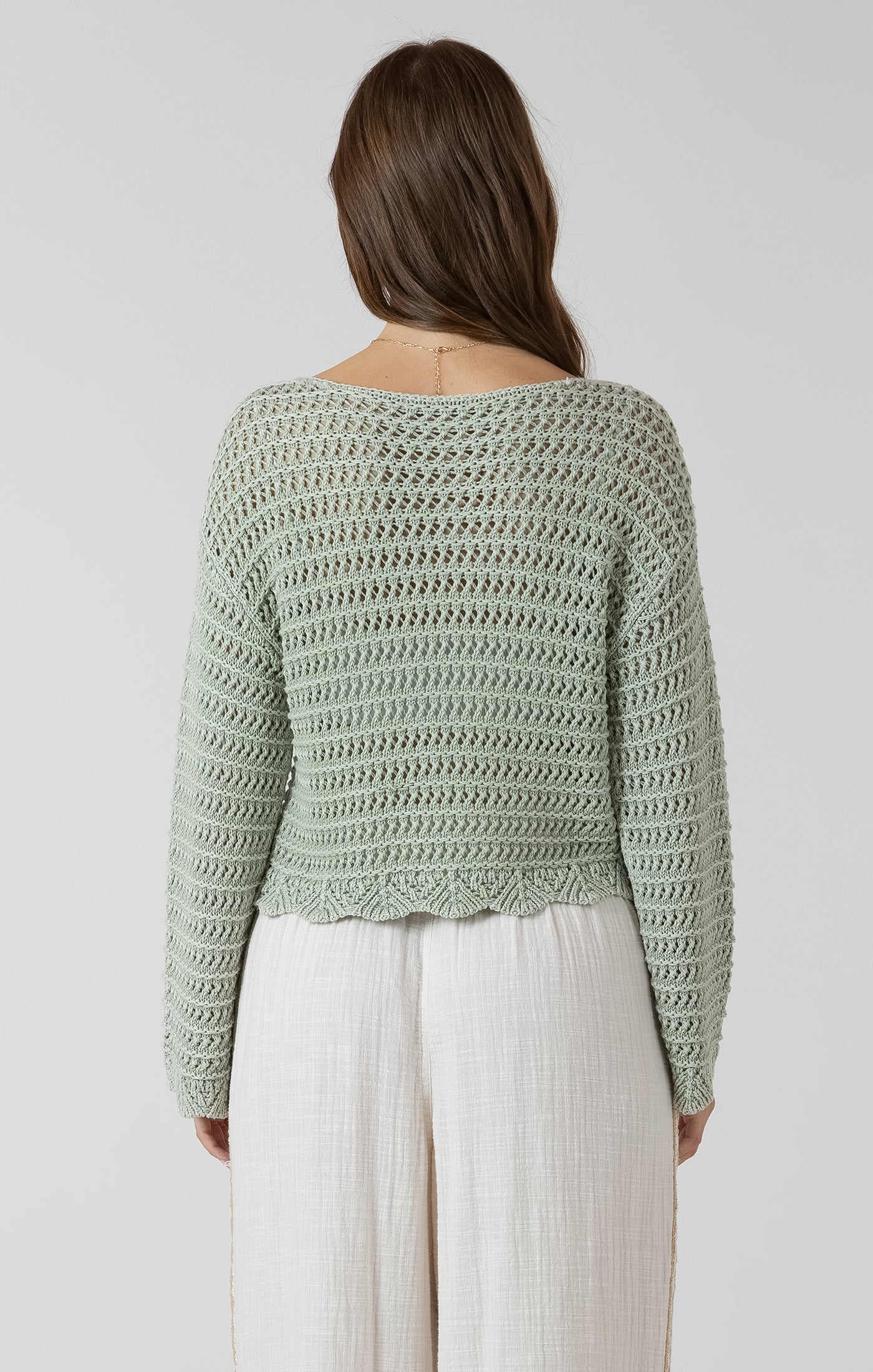 Woman wearing a green crochet sweater on a white background