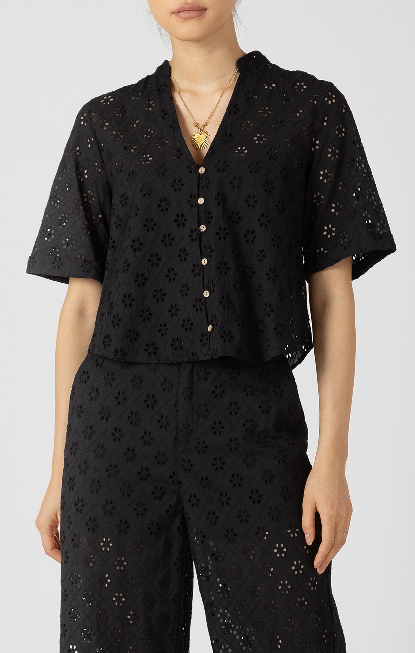 Person wearing a black eyelet blouse on a white background