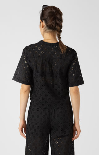 Person wearing a black eyelet blouse with a subtle pattern on a white background