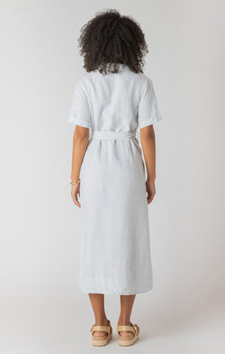Person wearing a white and blue stripe dress with a belt on a plain background