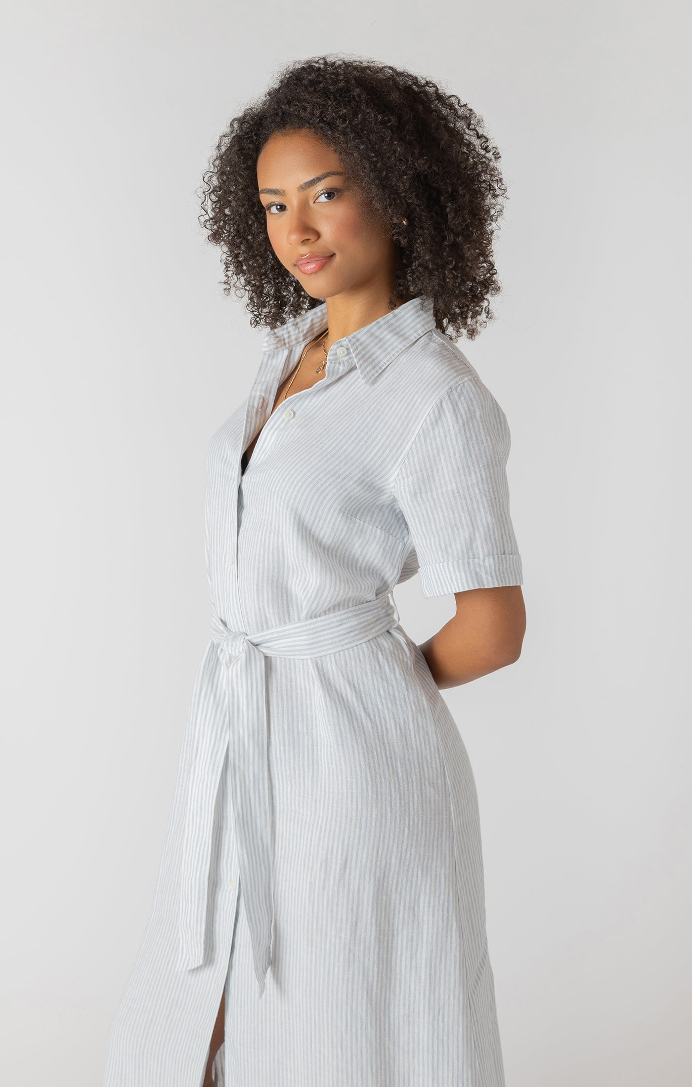 Woman wearing a light blue striped dress against a white background