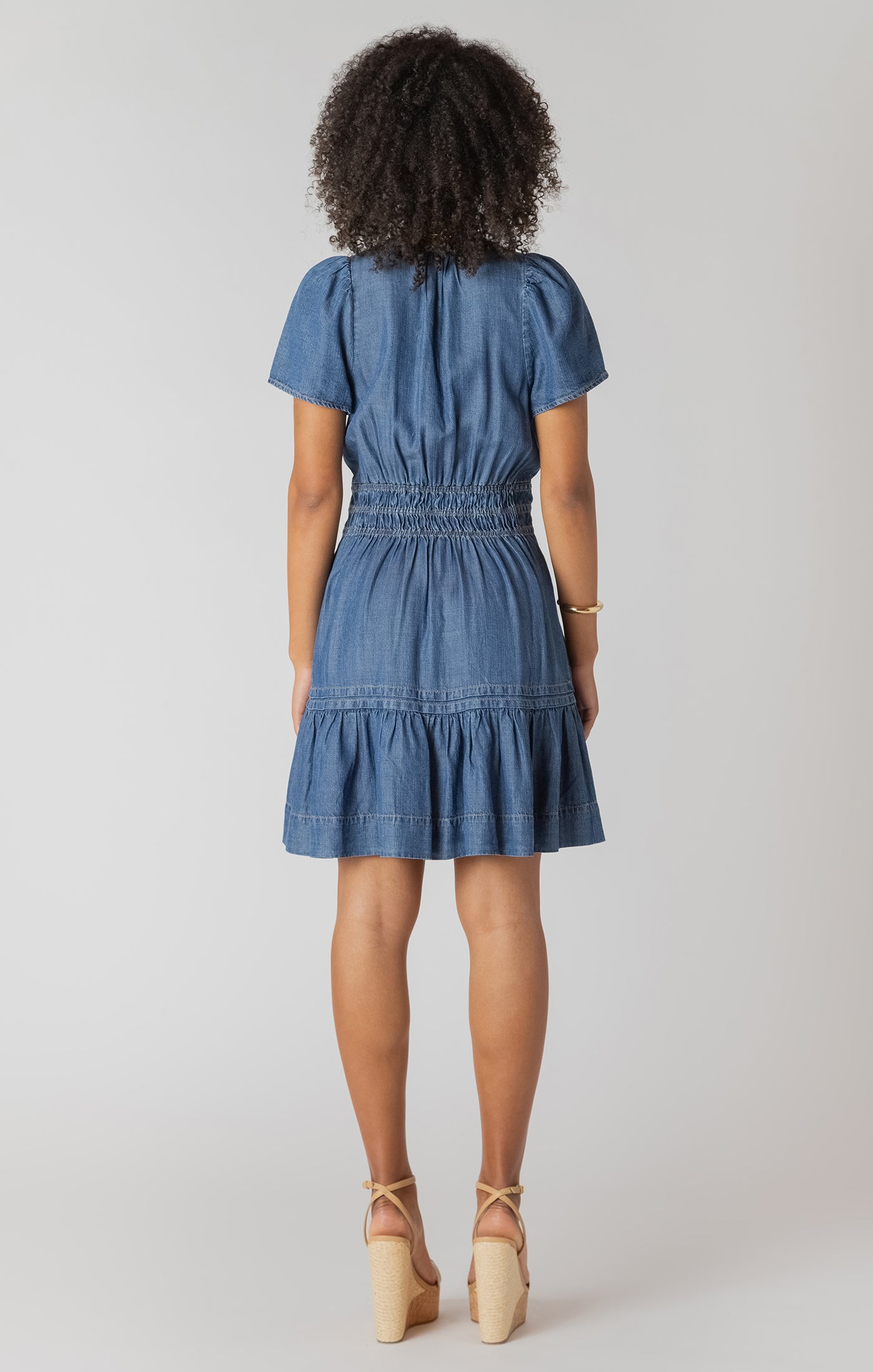 Woman wearing a blue denim dress against a white background