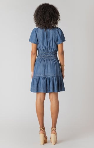 Woman wearing a blue denim dress against a white background