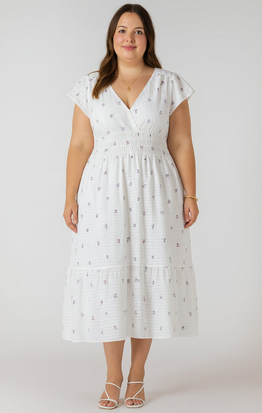 Woman wearing a white dress with a subtle pattern on a plain background