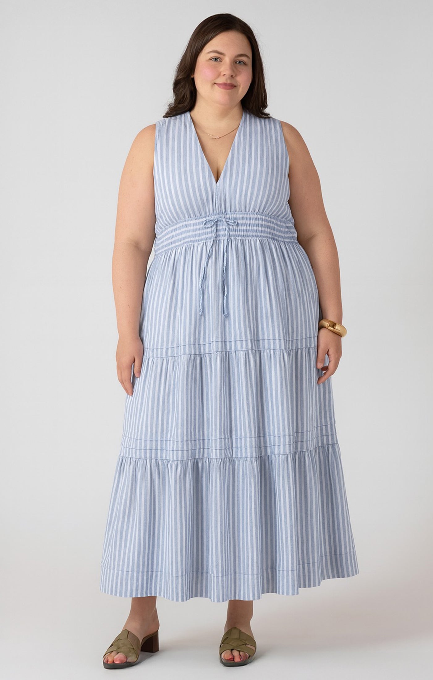 Woman wearing a blue and white striped dress against a plain background