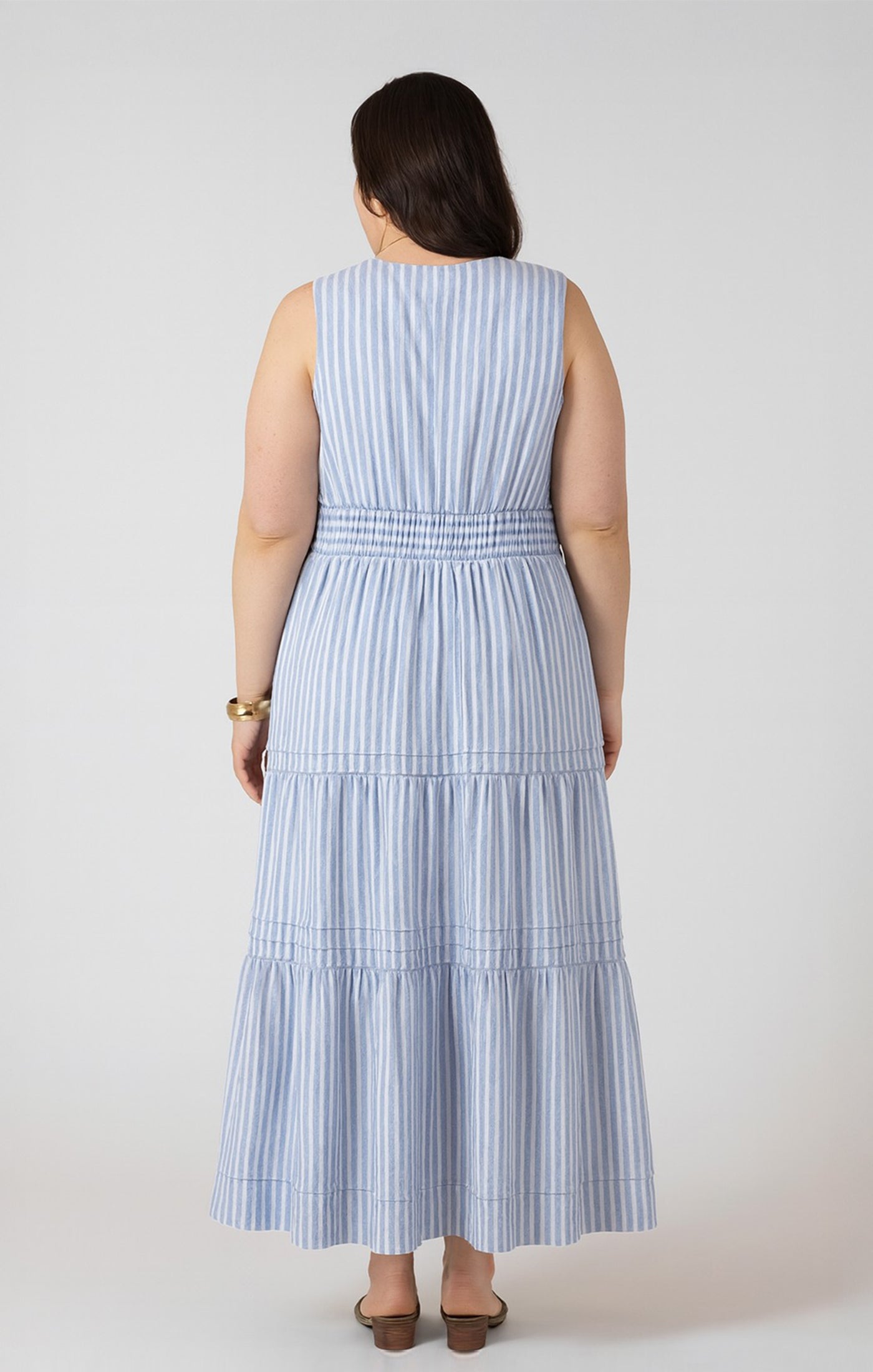 Woman wearing a blue and white striped dress against a plain background