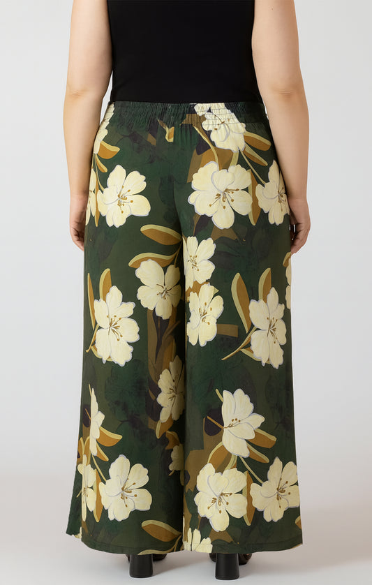 Green floral-patterned pants worn by a person on a white background