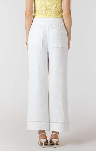 Person wearing white pants and a yellow top on a plain background
