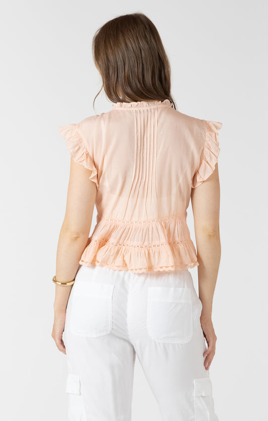Woman wearing a peach ruffled blouse against a white background