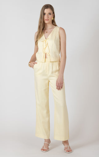 Woman wearing a light yellow top and pants against a white background