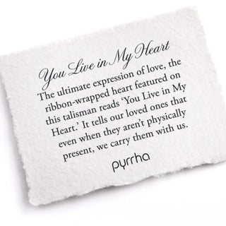 White ribbon-wrapped heart talisman with text on a white background