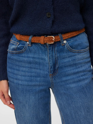Person wearing blue jeans with a brown belt on a plain background